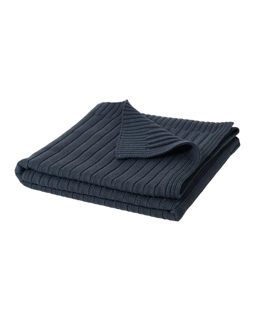 Folded navy blue 100% merino wool ribbed sweater on a light gray background