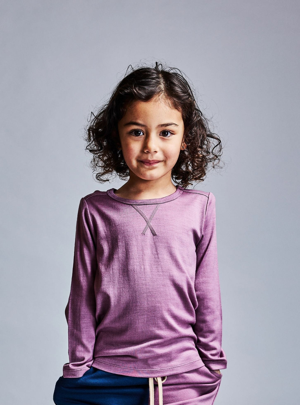 Child wearing a mauve pink merino wool long-sleeve shirt