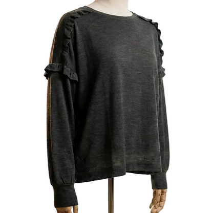 Mannequin wearing a dark grey merino wool womens sweater with frill detail in a photo studio setting with lighting equipment.
