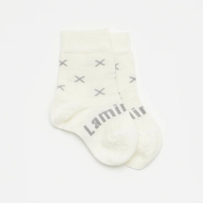 White merino wool baby sock with grey crosses and Lamington brand name on a light gray background