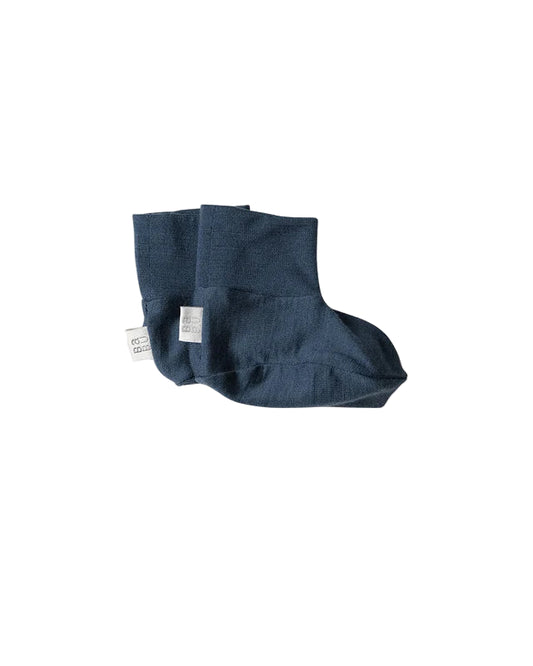 Pair of blue merino wool baby bootie socks on a light gray background