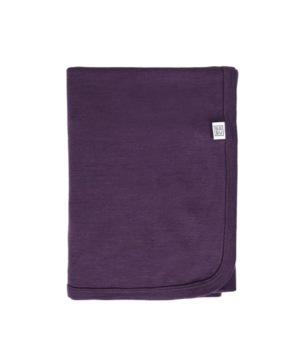 Purple 100% merino wool lightweight blanket with a brand label on a light gray background